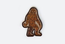 Load image into Gallery viewer, A patch with Sasquatch, they are brown with darker brown formline designs drawn across their body. the binding is dark brown