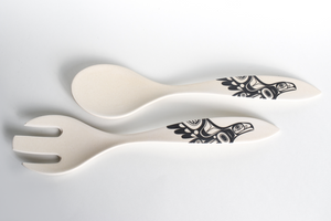 a serveware set, 1 spoon, and 1 fork, they are both off white with formline eagle design on the handles.